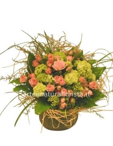 Cestino di vimini o ciotola di ceramica, composto da rose e verde pregiato.